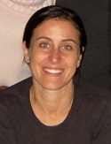A smiling woman with dark hair pulled back, wearing a black shirt.