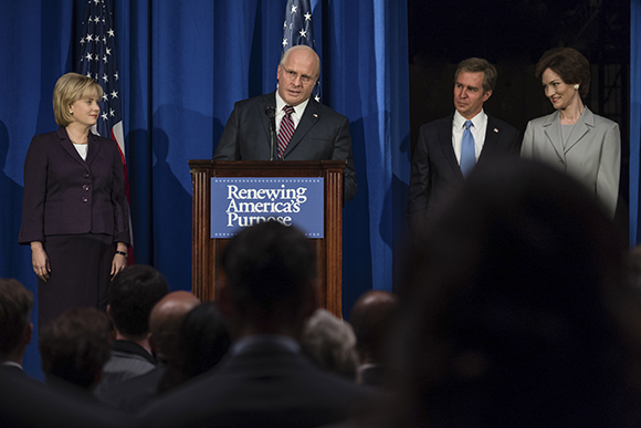A man speaks at a podium labeled 'Renewing America's Purpose' flanked by three other people.