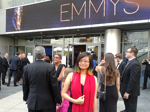 A group of people standing outside a building with a large digital sign reading EMMYS.