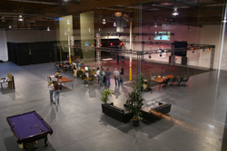 High-angle view of a large industrial loft with people, lounge areas, a pool table, and a stage setup.
