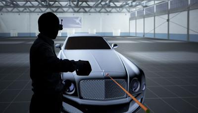 Silhouette of a person wearing a VR headset pointing a controller at a 3D model of a car in a virtual space.
