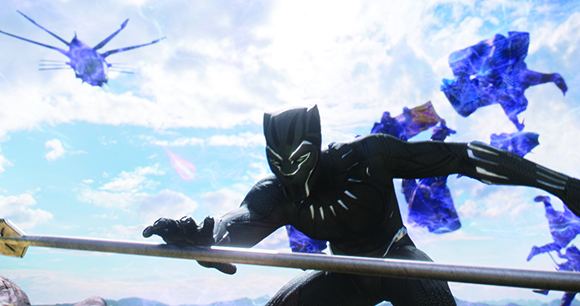Black Panther in a black suit crouches in a combat stance under a bright sky with floating blue energy fragments.