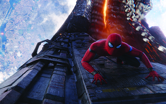 Spider-Man crawls along the side of a tall, metallic structure high above a sprawling city landscape.