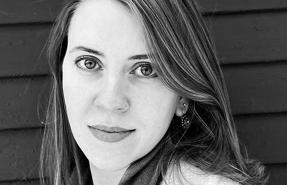 Black and white close-up portrait of a woman with long hair looking forward.