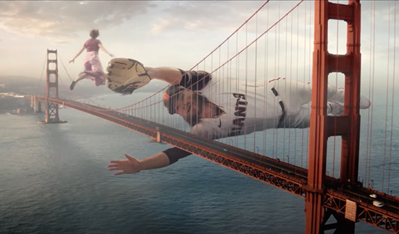 A baseball player lunges across the Golden Gate Bridge toward a person running in the distance.
