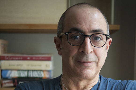 Close-up portrait of a man with short hair and dark-rimmed glasses looking at the camera.
