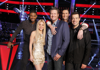 Five smiling people posing together on a brightly lit stage with red and black decor.