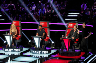 Four judges sit in large red chairs on a stage with 'I WANT YOU' signs in front of them.
