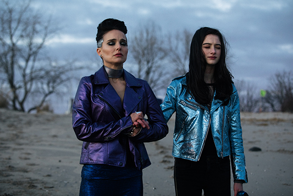 Two women stand in a desert; one wears a purple metallic jacket, the other a blue metallic jacket.