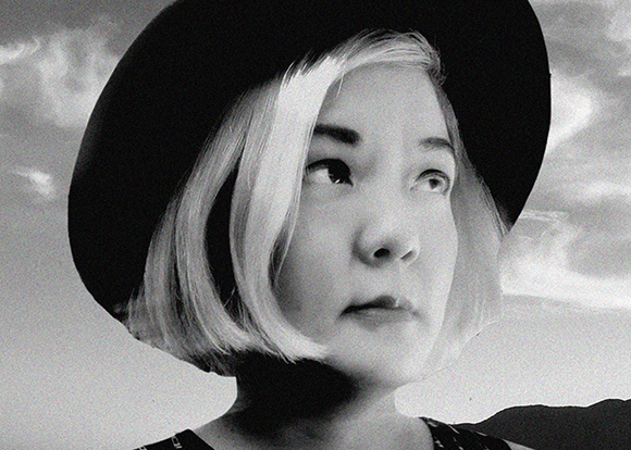 Black and white close-up portrait of a woman with short blonde hair wearing a large dark hat.