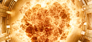 A massive, circular burst of bright orange and yellow flames filling a circular space.