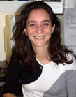 A smiling woman with long dark hair wearing a black and white top.