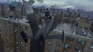 A dark, sleek drone flies over a brick apartment building toward a city skyline under a cloudy sky.