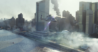 A helicopter flies over a city skyline with smoke rising from buildings near a river.