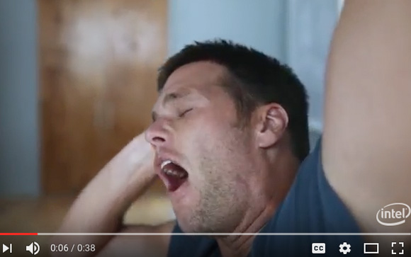 A man with short dark hair yawns with his mouth wide open and eyes closed.
