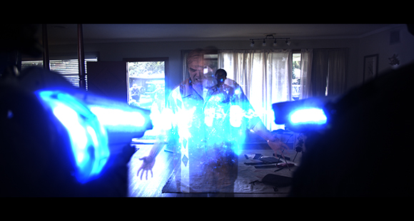 A person stands in a room facing two bright, glowing blue lights held in the foreground.
