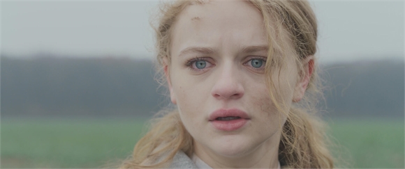 Close-up of a young woman with blonde hair and blue eyes looking forward with a sad expression.