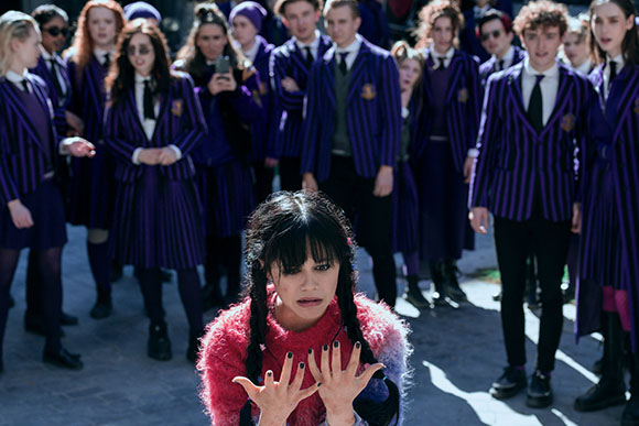 A group of students in purple striped uniforms standing behind a girl with dark braids.
