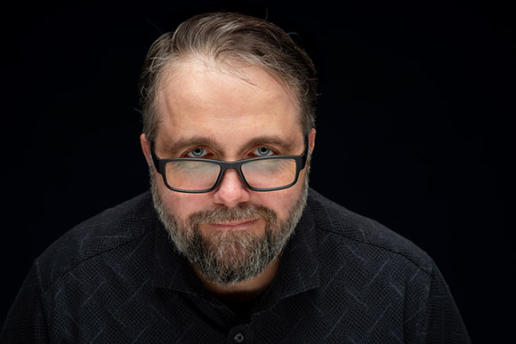 A man with short brown hair, glasses, and a salt-and-pepper beard looking directly at the camera.