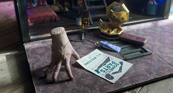 A prosthetic hand, a tube of cream, and a flyer that reads 'SOME OF YOUR PARTS' on a floral patterned surface.