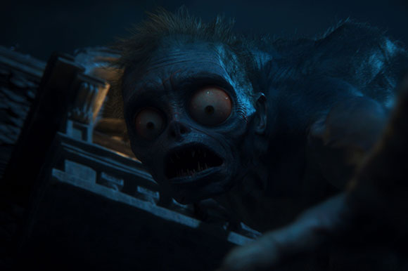 A close-up of a dark, creature with large bulging eyes and sharp teeth peering over an edge.