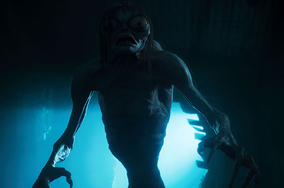 A thin, pale humanoid creature with large bulging eyes and long clawed hands reaches forward in blue light.