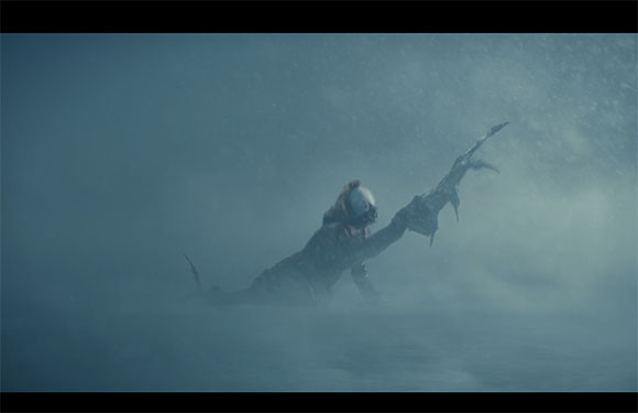 A person wearing a helmet and dark clothing struggles through a thick, snowy blizzard.