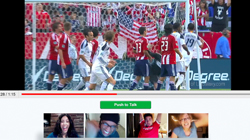 Soccer players in red and white uniforms celebrate on a field near an American flag.