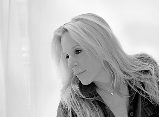 Black and white portrait of a blonde woman looking downward with a contemplative expression.