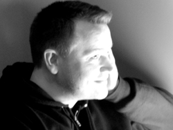 Black and white portrait of a man looking off to the side with his hand against his face.