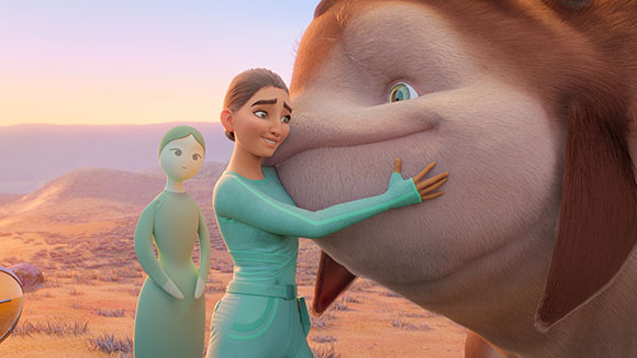 An animated woman in a teal jumpsuit hugs the cheek of a large, brown, furry creature in a desert landscape.