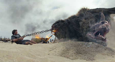 A man sits on sand holding a heavy chain connected to a large, dark, fanged beast in a dusty landscape.