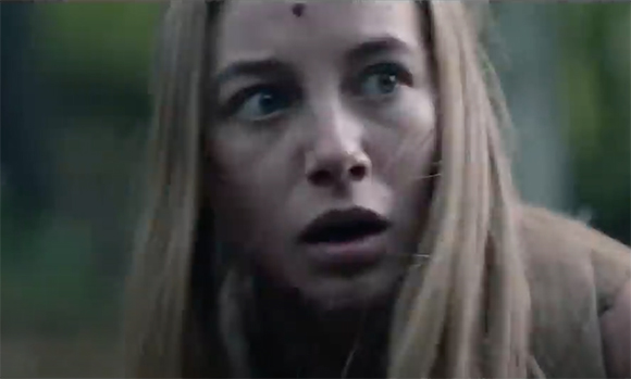 A blonde woman looks off-camera with wide eyes and an open mouth in a state of shock.