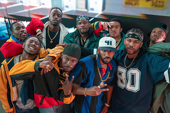 A group of men in colorful streetwear and hats posing closely together for a group portrait.