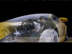 Double exposure of a man and woman superimposed over a yellow sports car against a black background.