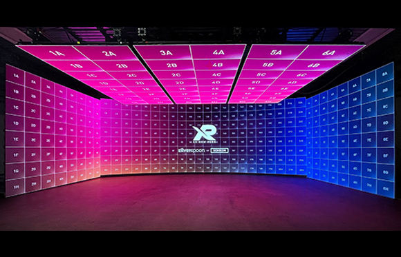 A large, curved LED screen wall displaying a grid of numbered panels in pink and blue gradients.