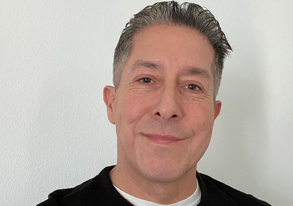 A middle-aged man with short, dark, salt-and-pepper hair smiling at the camera.