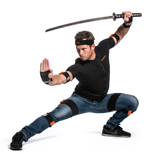 A man in a black shirt and jeans lunges while holding a katana above his head.