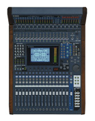 A large blue digital audio mixing console with numerous sliders, knobs, and a central display screen.