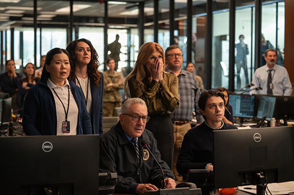 A group of diverse people in a modern office looking toward something off-camera with worried expressions.