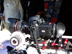 A professional camera with a large lens and viewfinder attachment is mounted on a rig.
