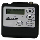 A black Zaxcom device with a silver faceplate, digital screen, and four control buttons.