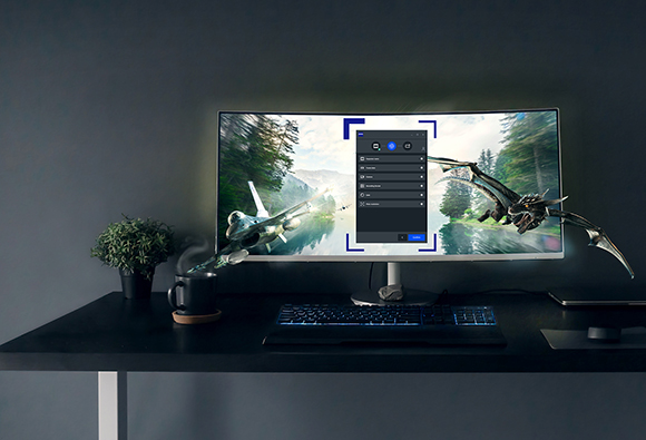 A curved monitor on a dark desk shows a jet and a dragon appearing to fly out of the screen.