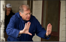 A man in a blue jacket holds his hands up in a defensive martial arts stance.