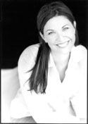 Black and white portrait of a smiling woman with long dark hair wearing a white shirt.