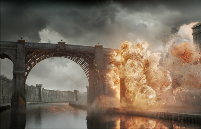 A massive orange and white explosion occurs next to a stone arch bridge over a dark canal under a cloudy sky.