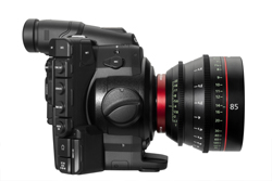 Side view of a black professional cinema camera equipped with a large prime lens.