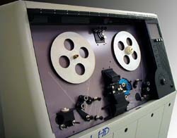 A large, light-colored reel-to-reel audio tape recorder with two silver metal reels.