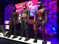 Three superhero costumes, Black Panther, Captain America, and Ant-Man, stand on display.