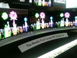 Several curved OLED televisions are displayed in a row, each showing a vibrant, abstract visual with colorful lights and shap